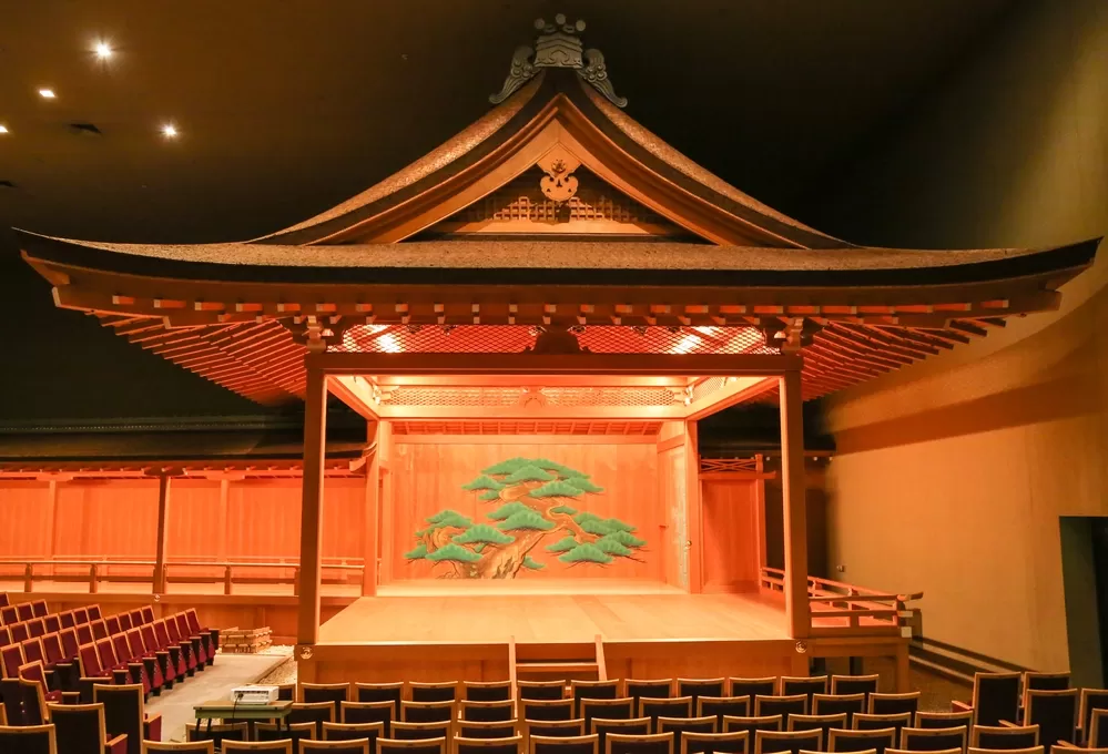 A Noh theater.  A well designed Japanese theater made of wood with a tree on the back wall.