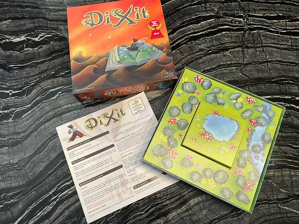 The Dixit board game box opened to show its components.