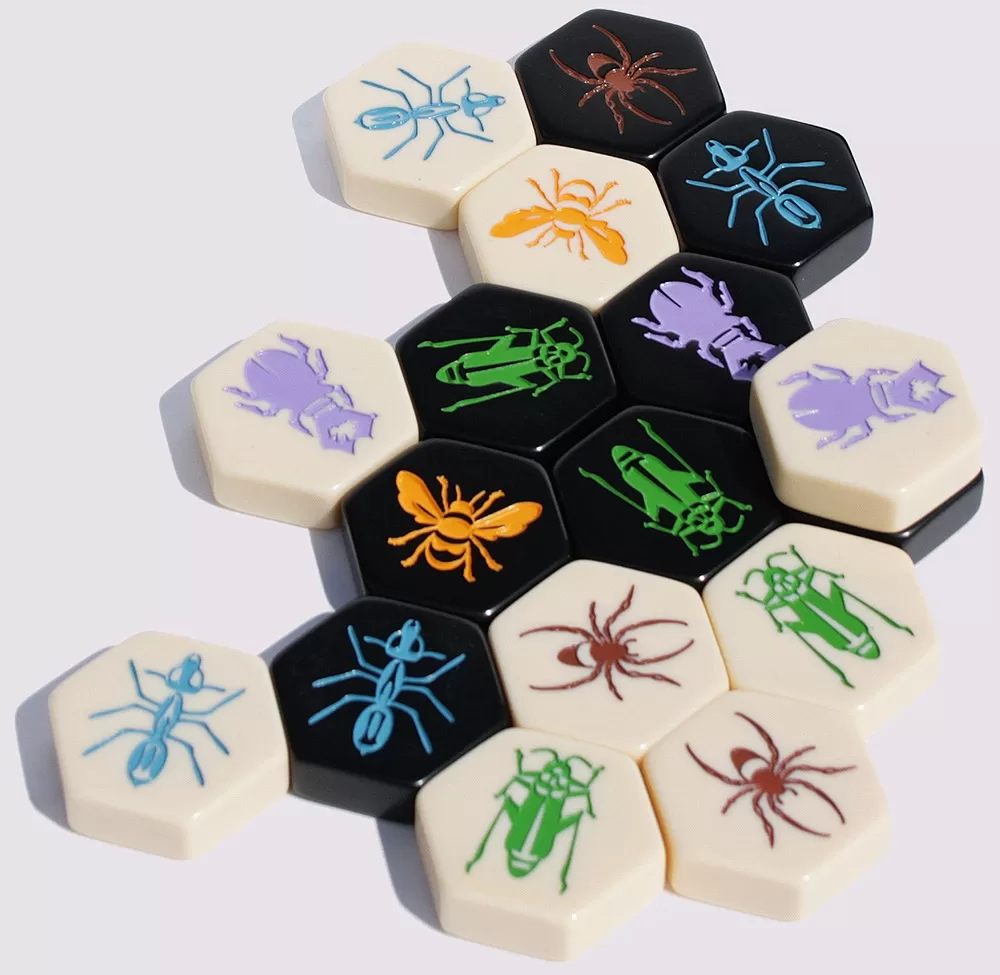 Closeup of Hive.  A board game with unique black and whitehexogonal tiles with colored insects on them.