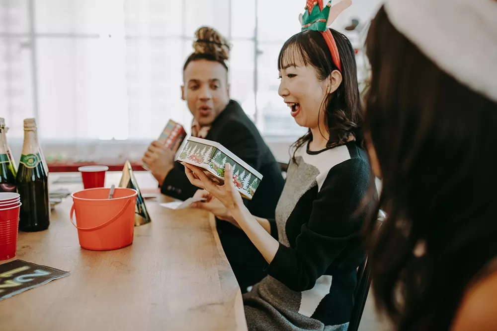 A woman wearing a Christmas hair band excited about opening a present.
