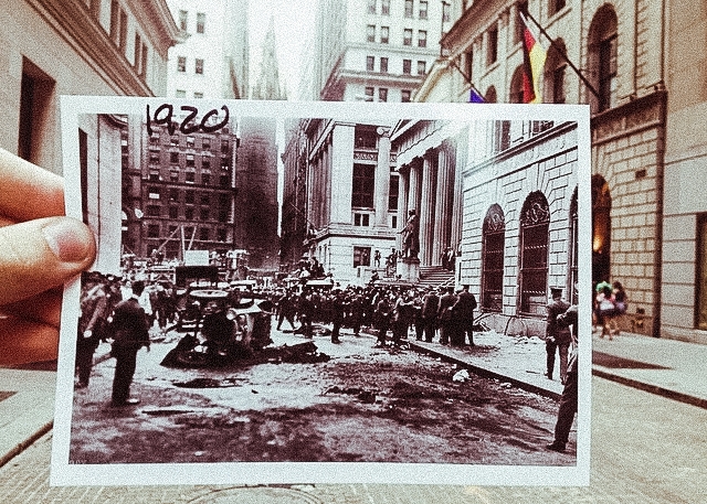 A wall street photo from 1920 is held by hand to align perfectly with its modern setting.