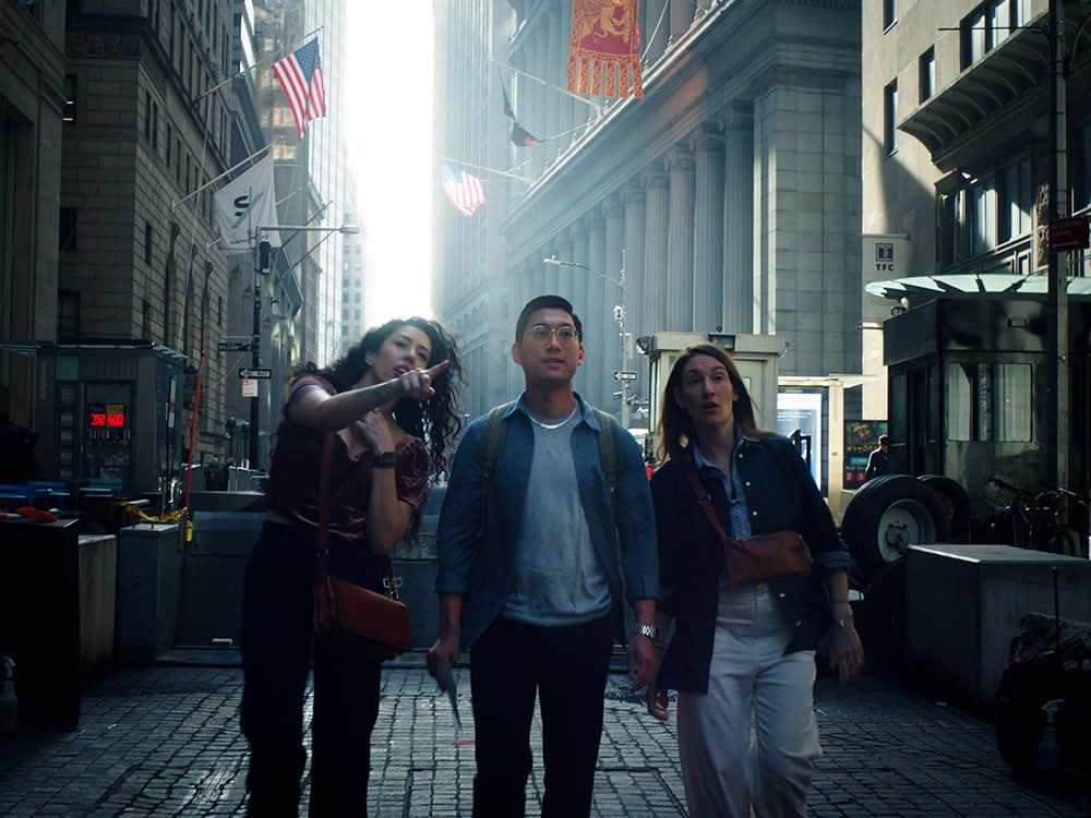 Three people walking on the streets of New York while a woman points at an off camera.